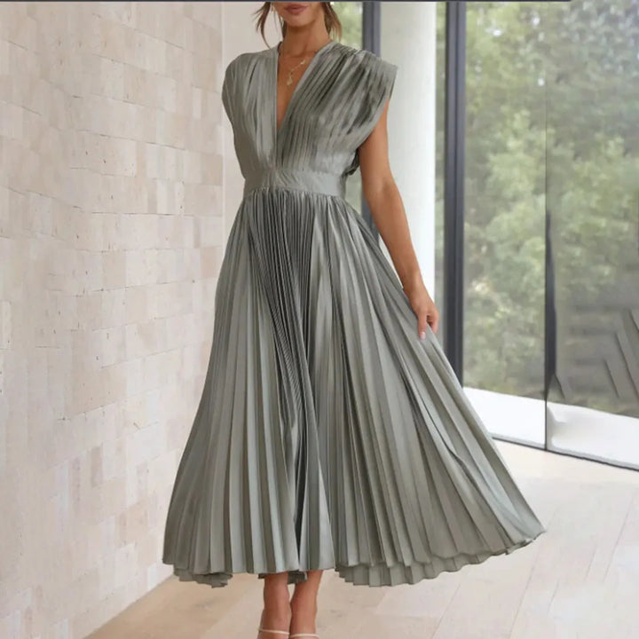 Model posing in a silver pleated midi dress with shimmering pleated fabric