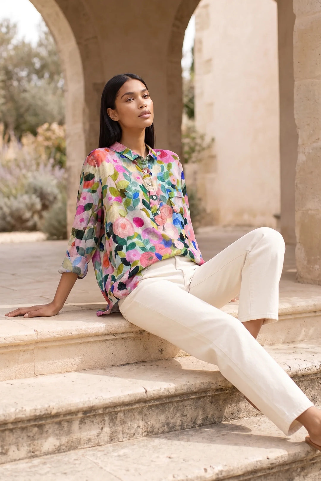 Model wearing a floral print blouse in an outdoor lifestyle setting