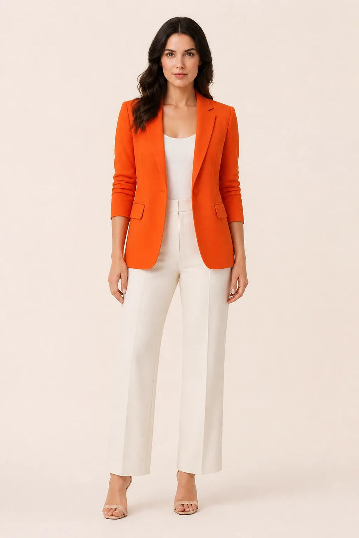 Orange open-front blazer with notch lapels worn by a model in a contrapposto stance