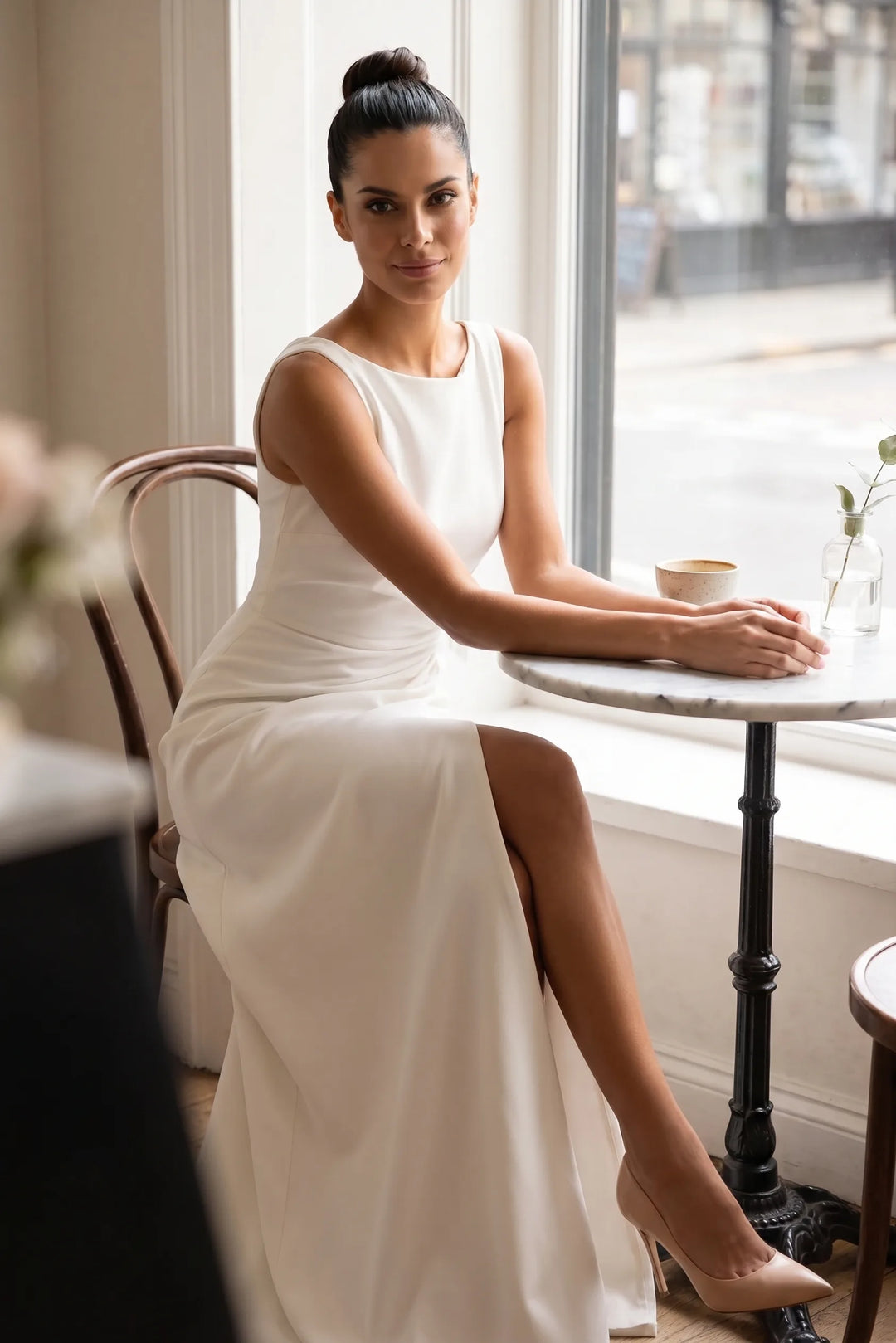 Model in white ruched gown with slit in a second outdoor lifestyle setting