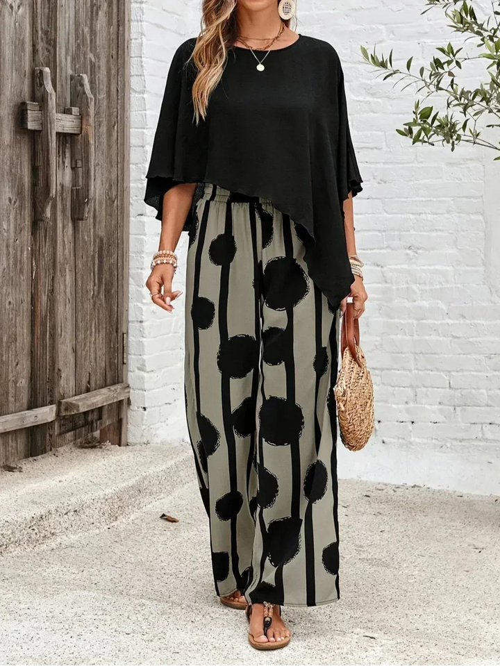 Close-up detail of black batwing sleeve fabric and trouser waistband
