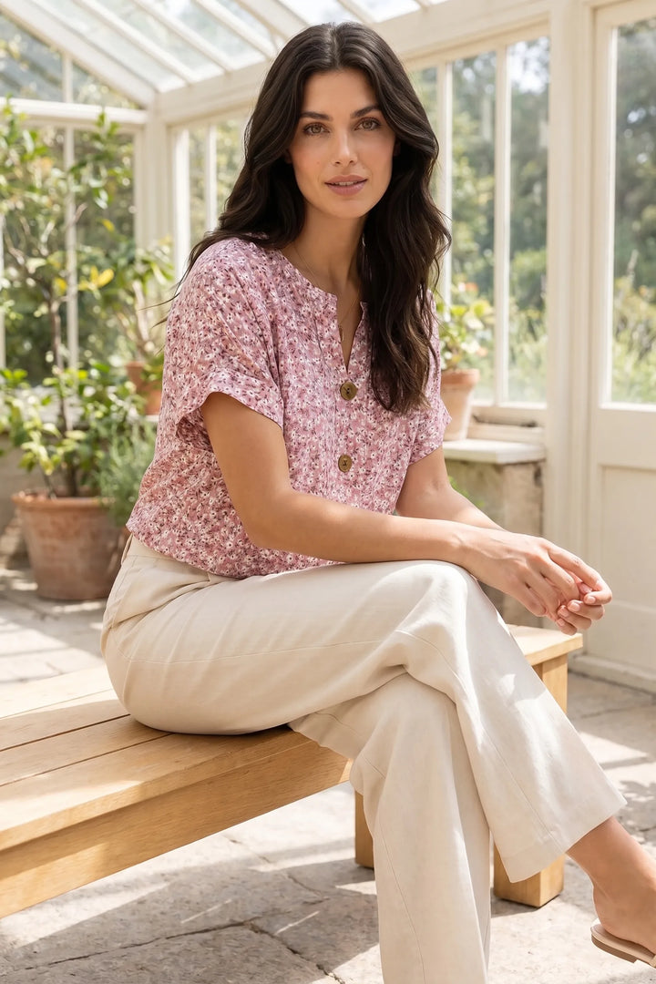 Model wearing a ditsy floral button blouse in an outdoor lifestyle setting