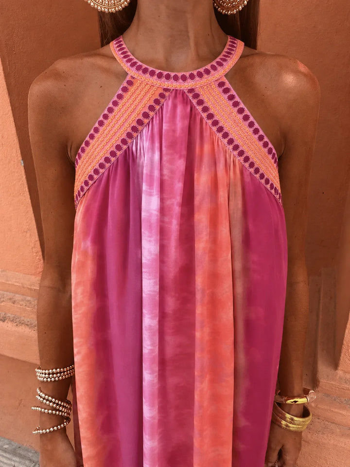Woman wearing a multicolor embroidered halter maxi dress, side profile view