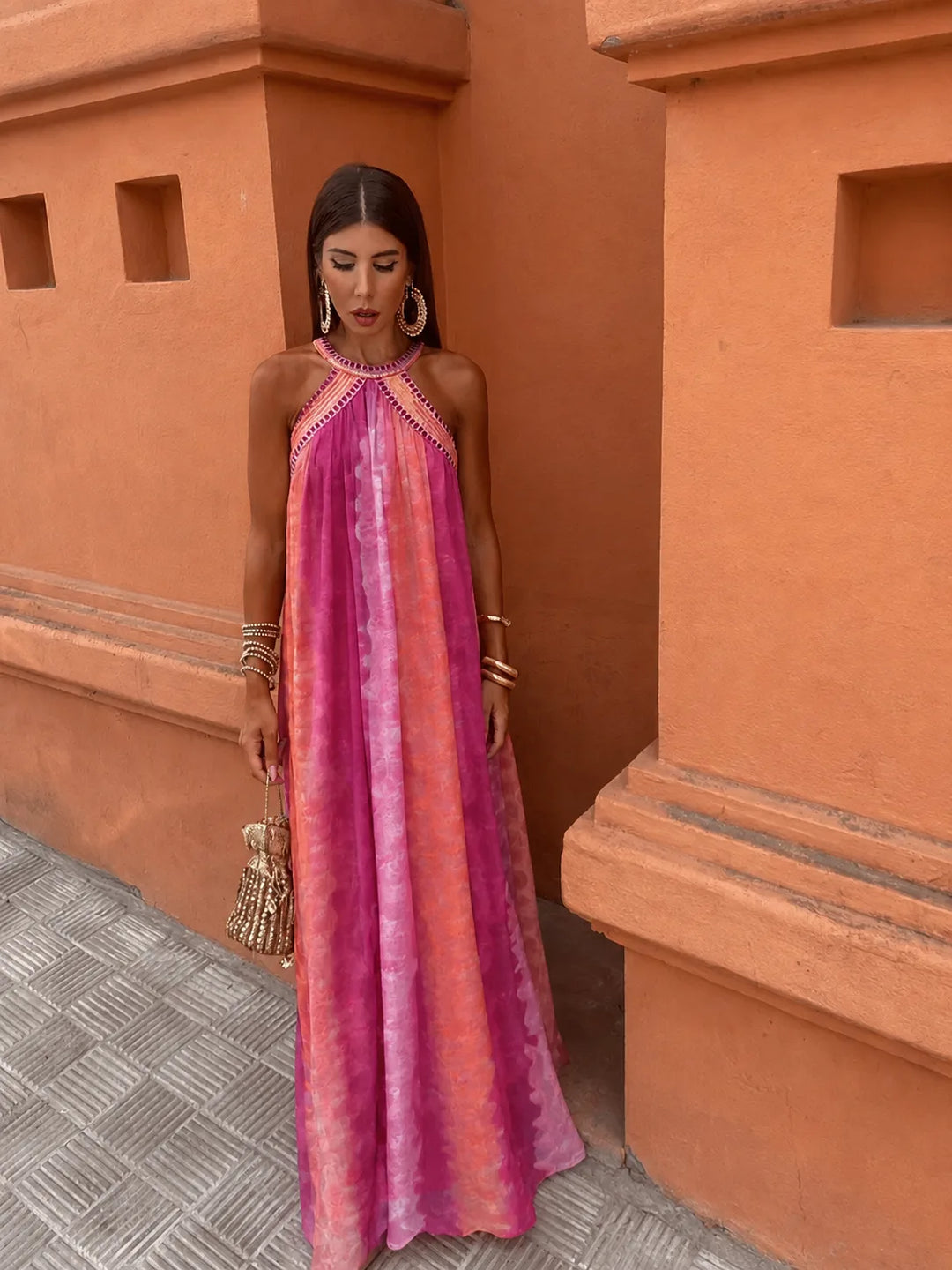Woman wearing a multicolor embroidered halter maxi dress, turned three-quarters