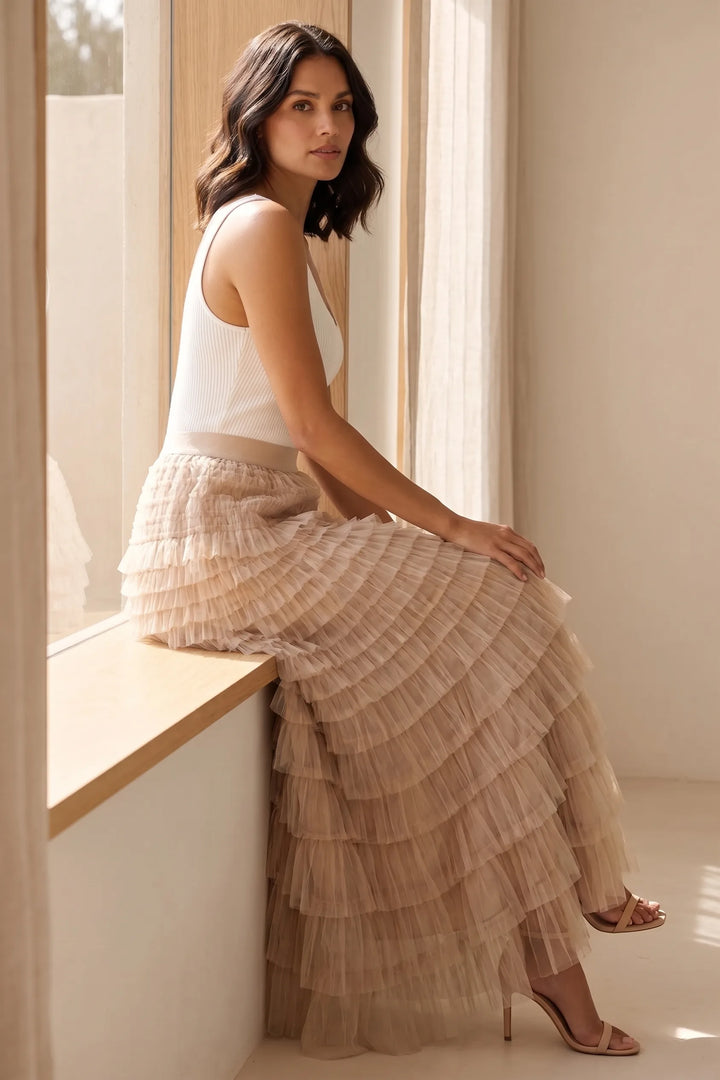 Model wearing a beige tiered tulle maxi skirt in an outdoor lifestyle setting