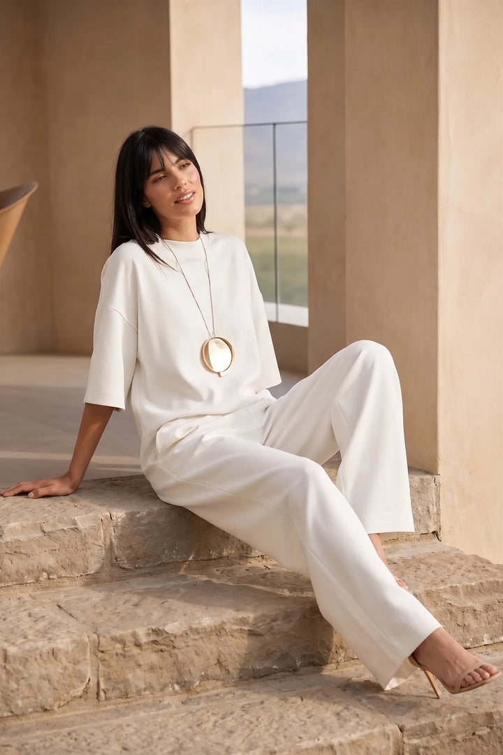 Model wearing white wide-leg jumpsuit in outdoor lifestyle setting