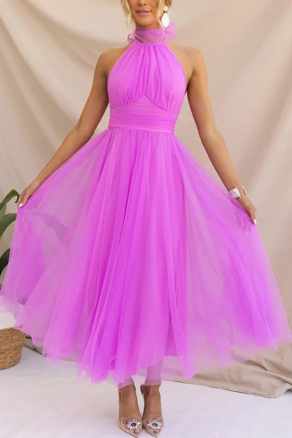 Model facing forward in a dark pink tulle halter midi dress with a full layered skirt