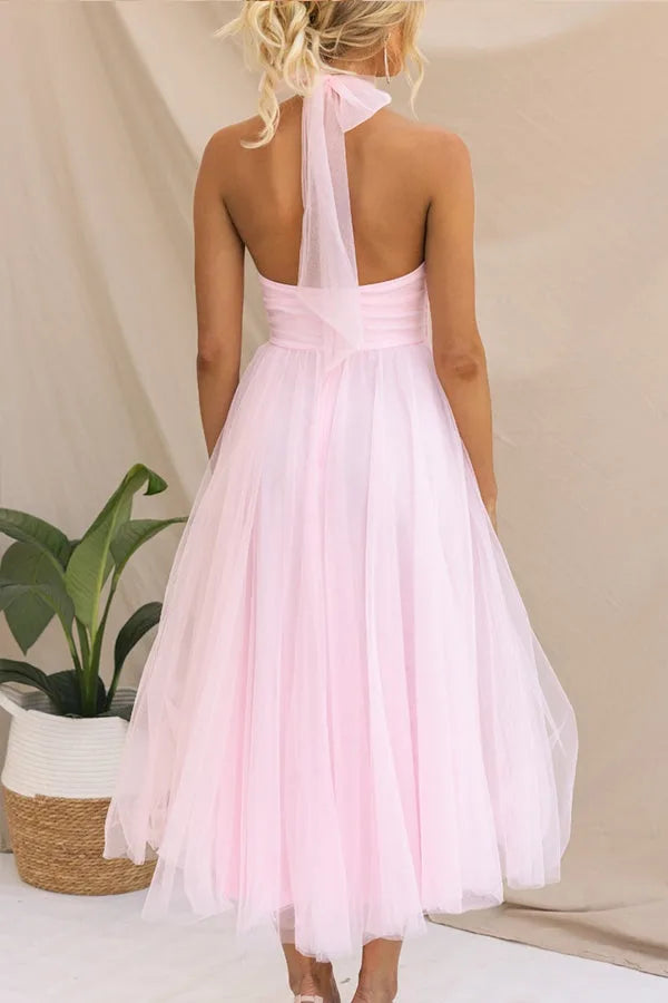 Model wearing a dark pink tulle halter midi dress highlighting the halter neckline