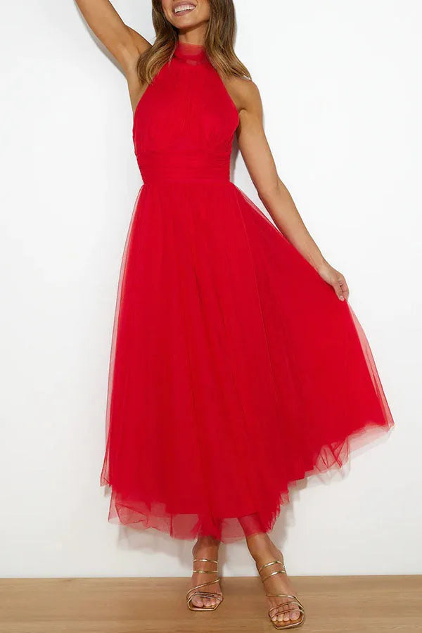 Model posing in a dark pink tulle halter midi dress with ruched halter bodice
