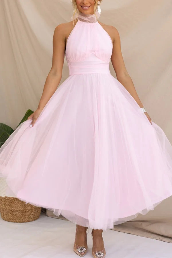 Model wearing a pink tulle halter midi dress with a full tiered skirt