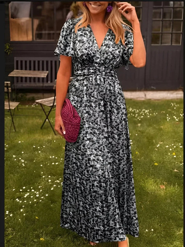 Woman wearing a black flutter sleeve maxi dress with tiered skirt in a full-length pose