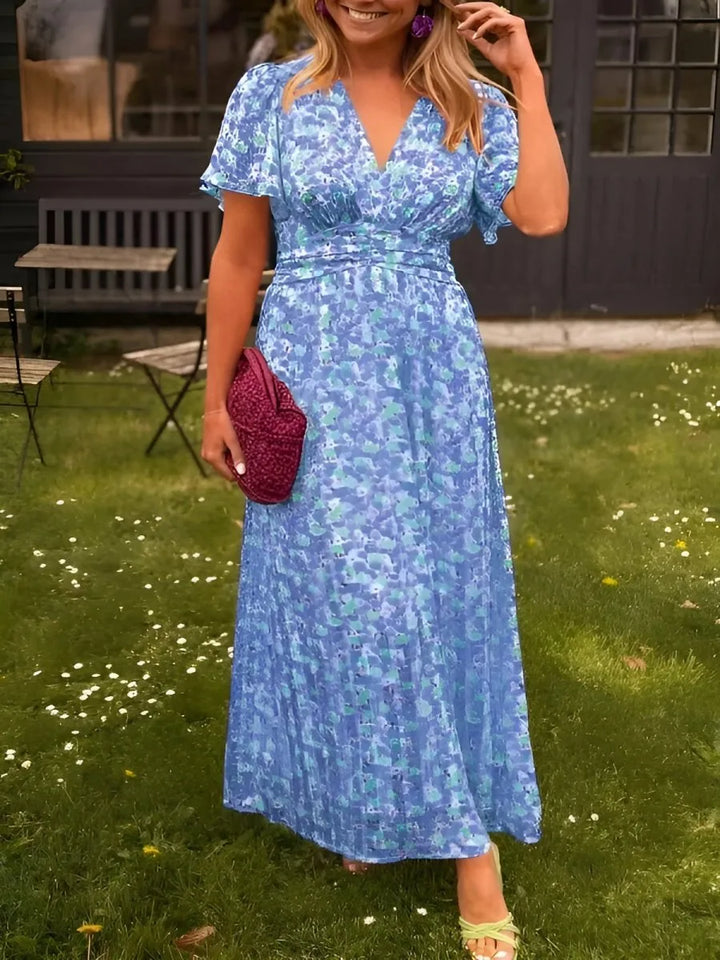 Woman wearing a blue flutter sleeve maxi dress with flowing skirt in a full-length pose