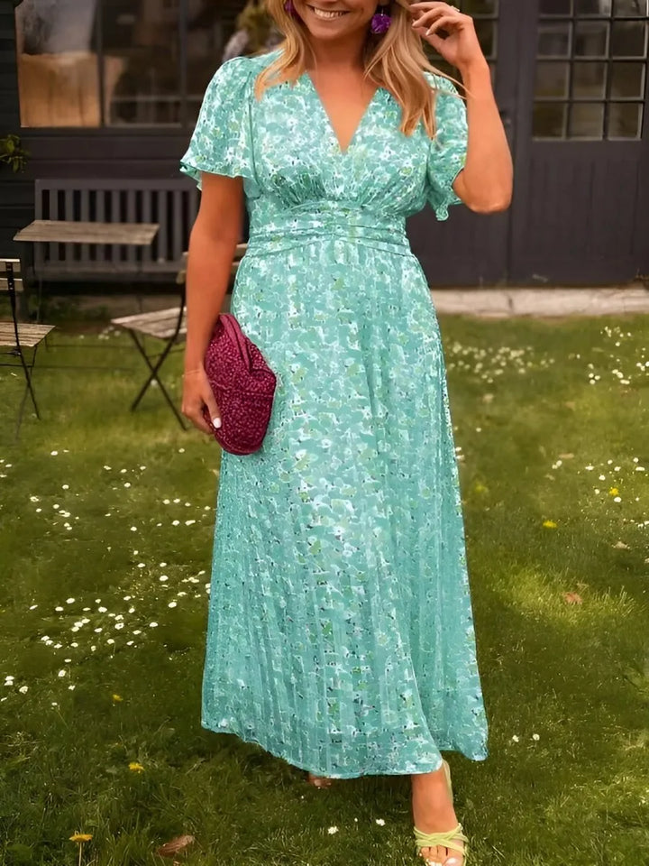 Woman modeling a green flutter sleeve maxi dress with elegant draping in a full-length view