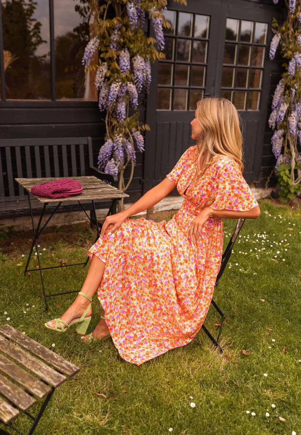 Woman in an orange flutter sleeve maxi dress posed at a three-quarter turn showing silhouette