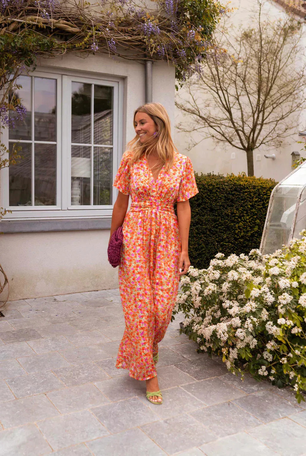 Woman modeling an orange flutter sleeve maxi dress in a relaxed full-length pose