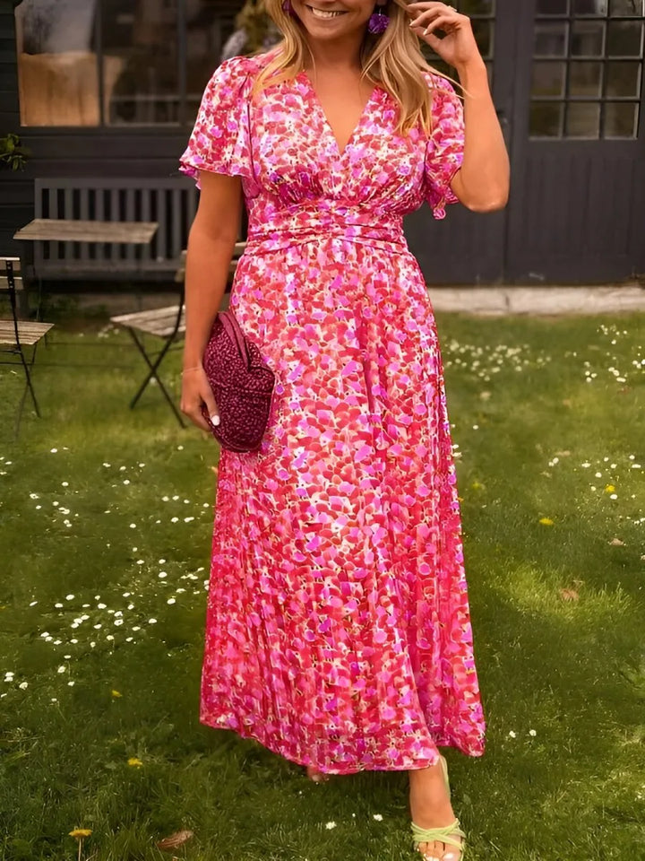 Woman in a pink flutter sleeve maxi dress with delicate flutter sleeves and tiered skirt
