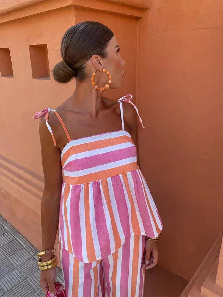 Woman posing in a blue striped peplum two-piece set, alternate angle
