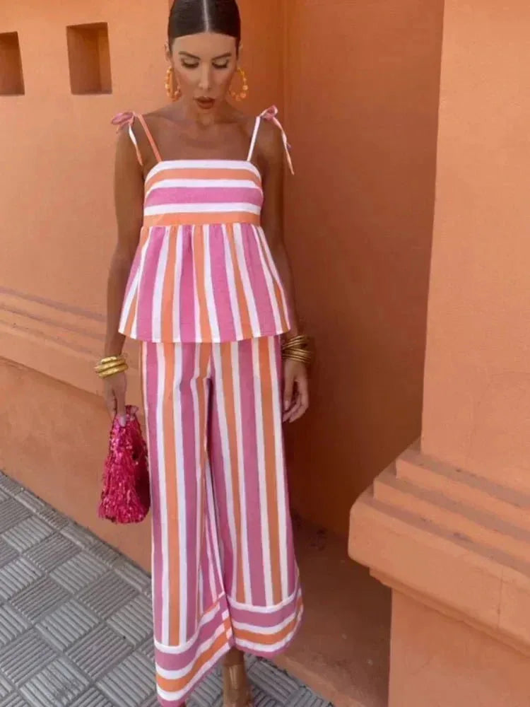 Woman in a three-quarter turn wearing a pink striped peplum top and skirt set