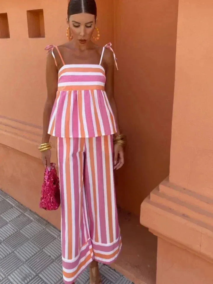 Woman in a three-quarter turn wearing a pink striped peplum top and skirt set