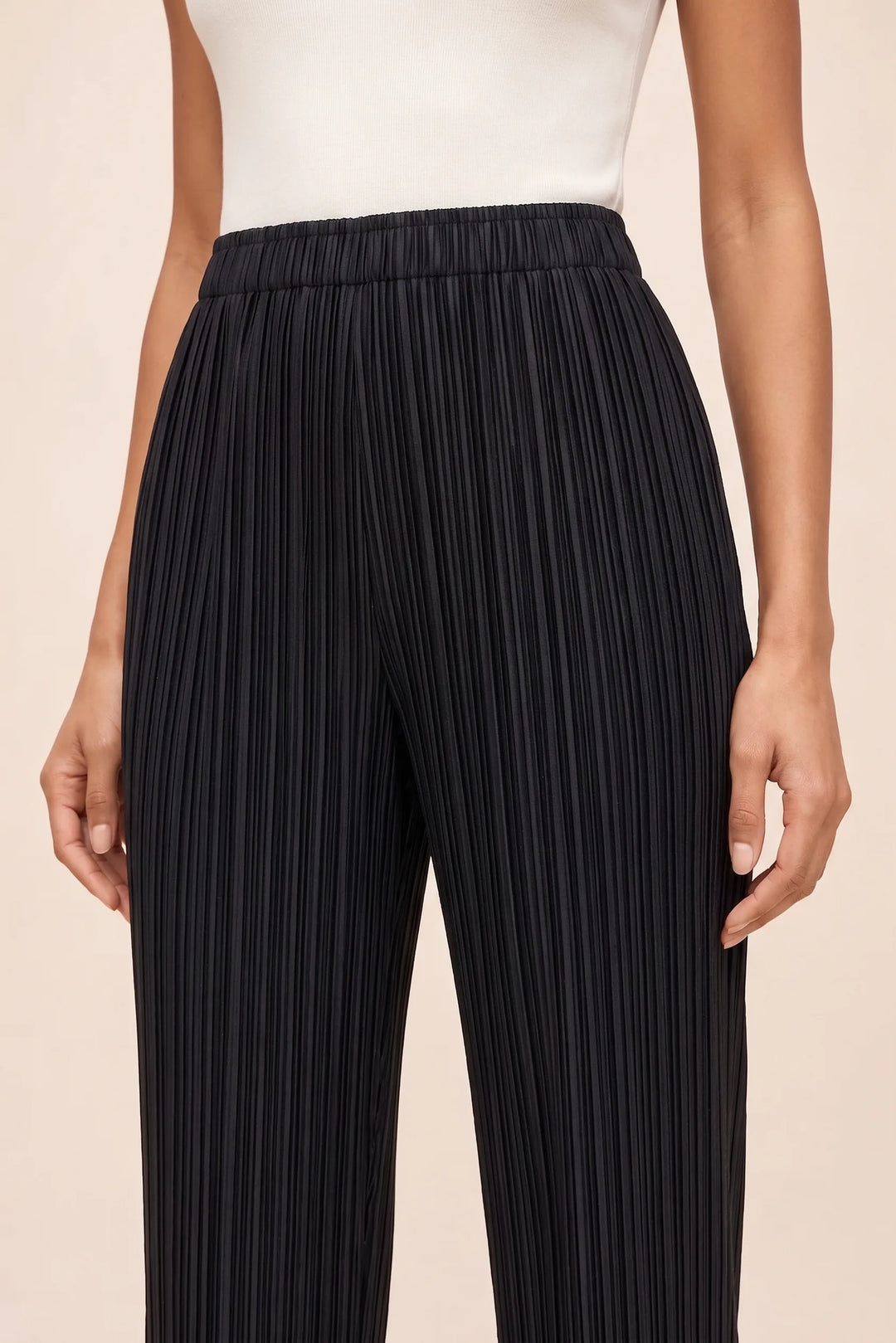 Close-up detail of black pleated cropped pants showing fabric and pleat texture