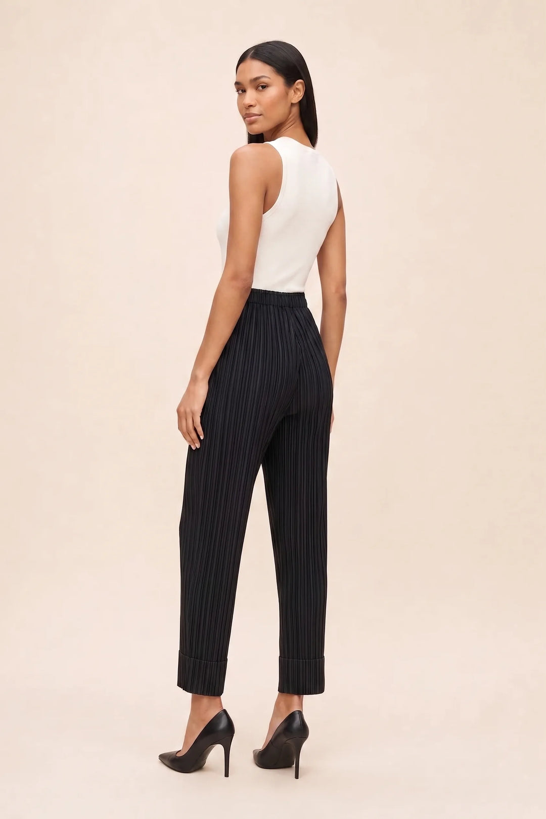 Black pleated cropped pants on a model in a three-quarter turn