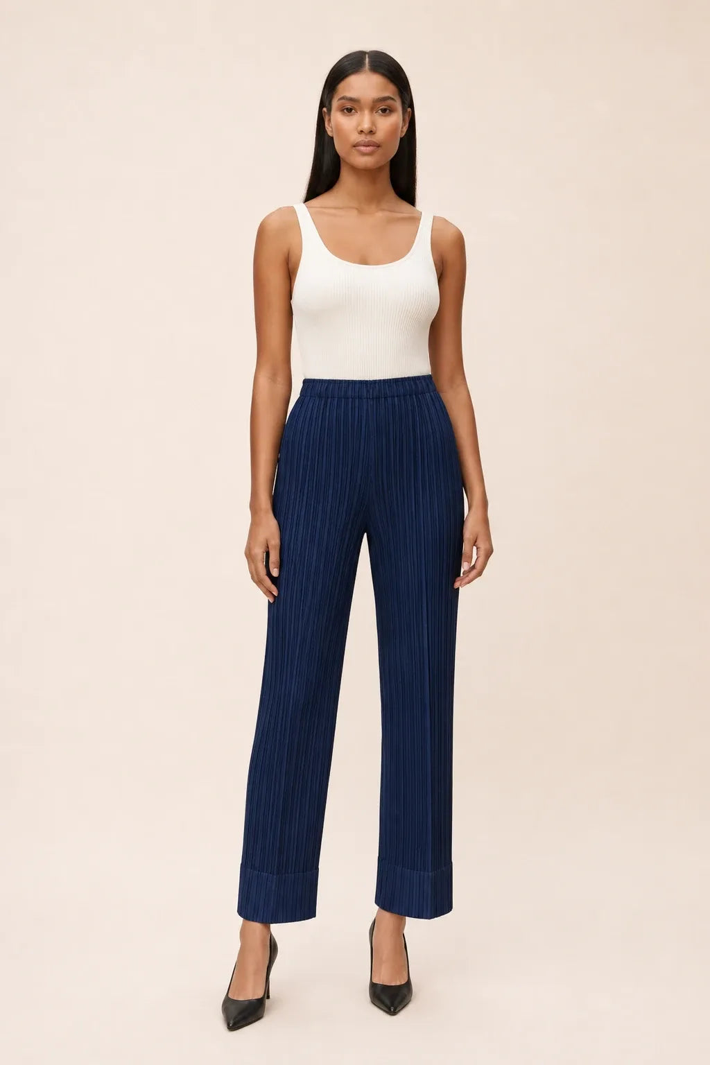 Deep blue pleated cropped pants on a model in a contrapposto stance