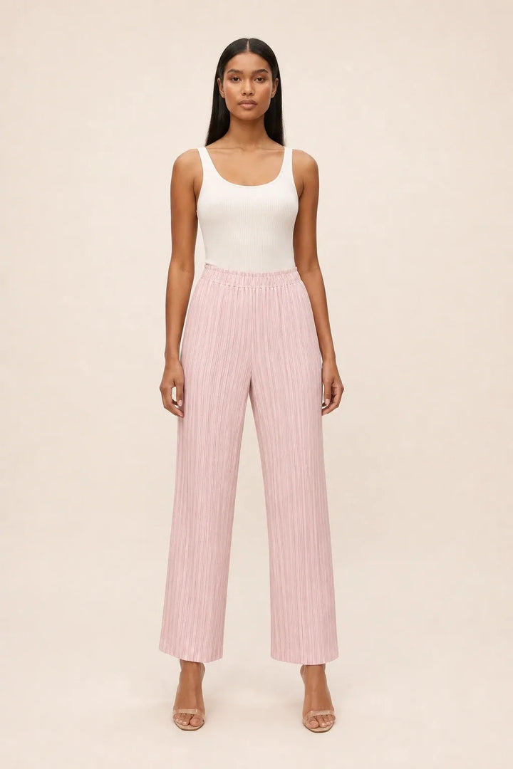 Pink pleated cropped pants on a model in a contrapposto stance