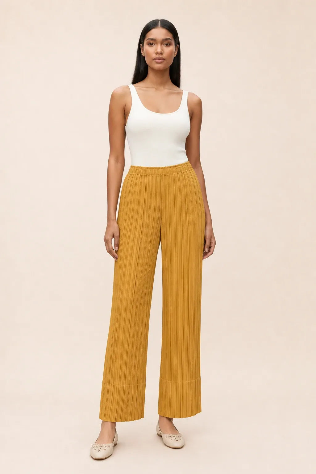 Yellow pleated cropped pants on a model in a contrapposto stance