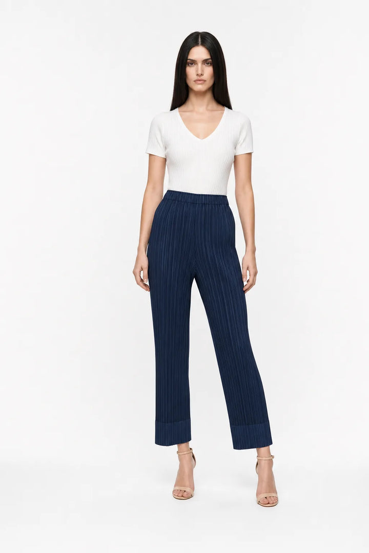 Deep blue pleated cropped trousers on a model in a contrapposto stance