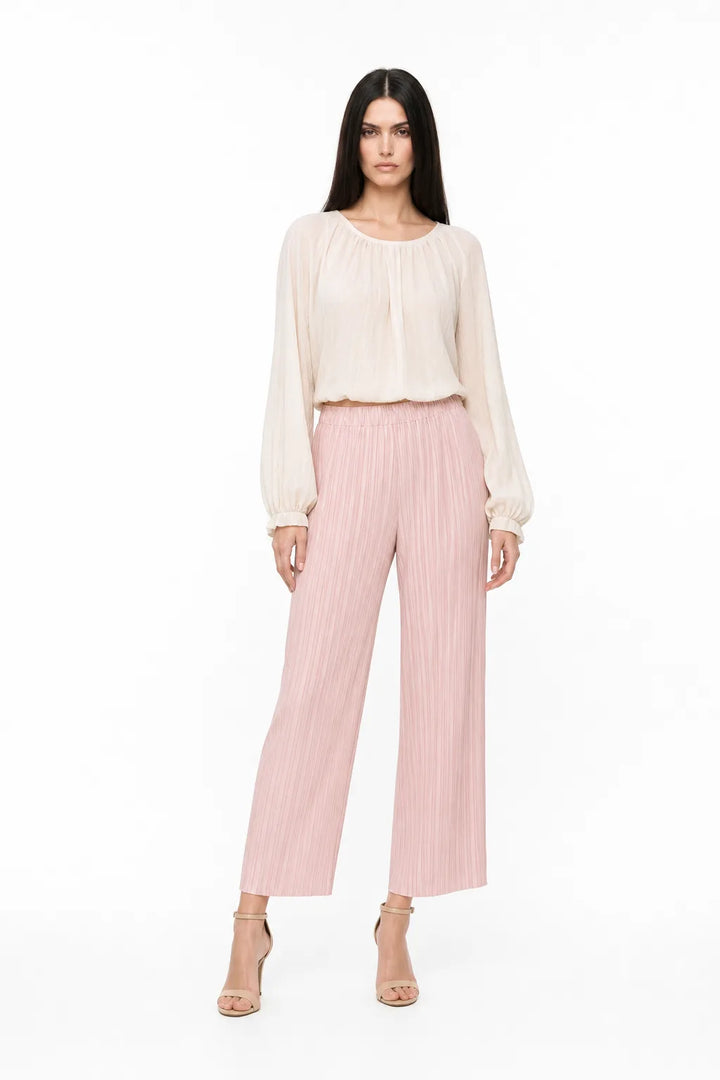 Pink pleated cropped trousers on a model in a contrapposto stance