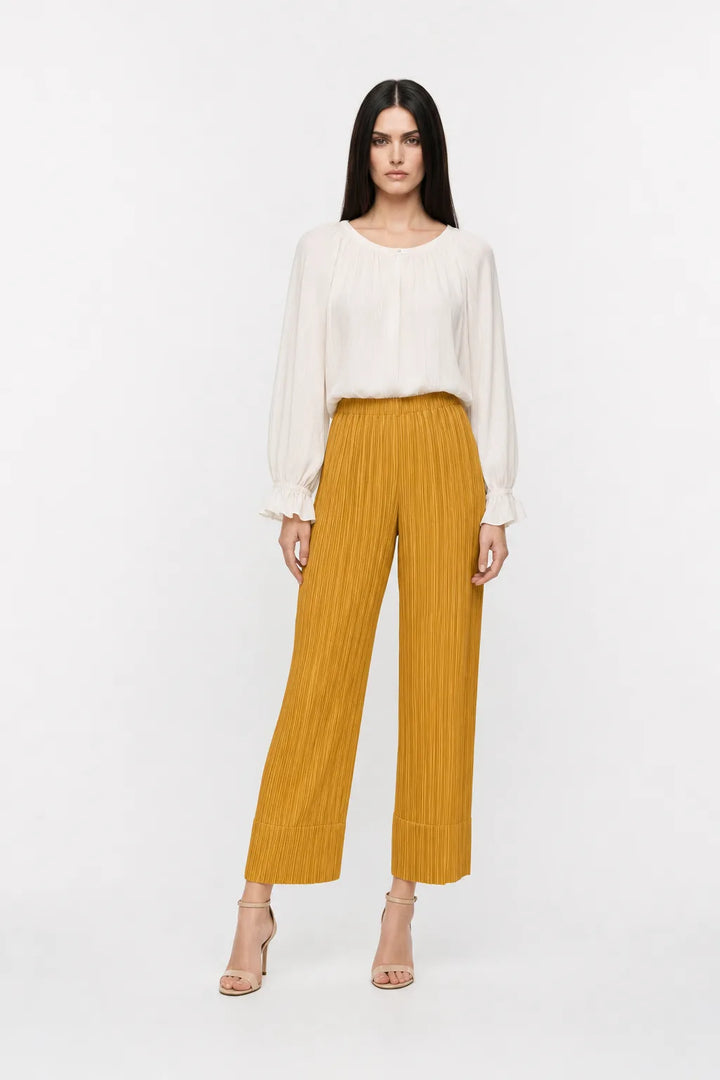Yellow pleated cropped trousers on a model in a contrapposto stance