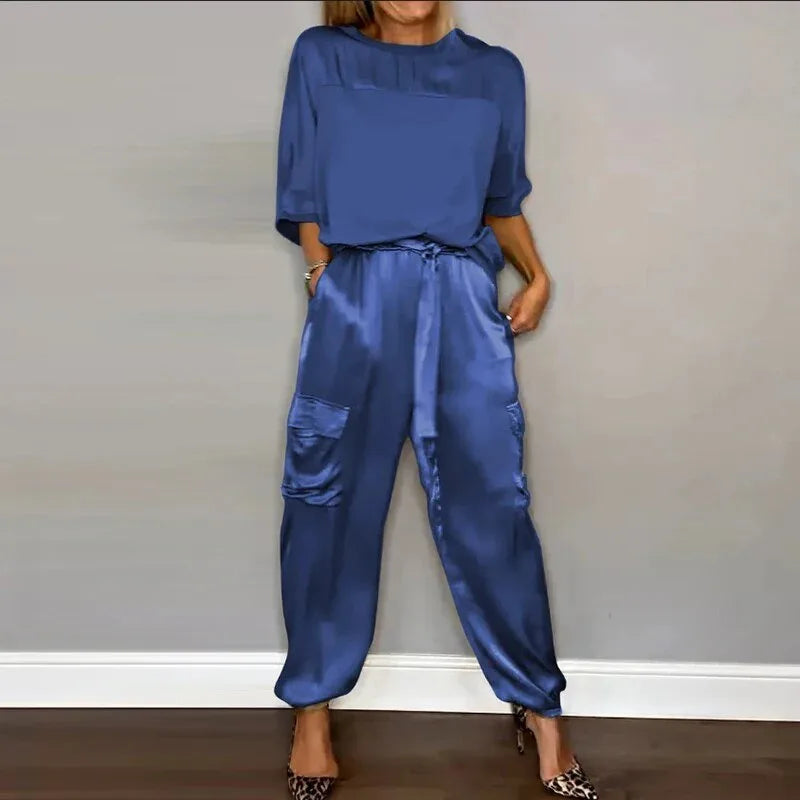 Model at a three-quarter turn wearing a blue satin cargo jacket and wide-leg pants