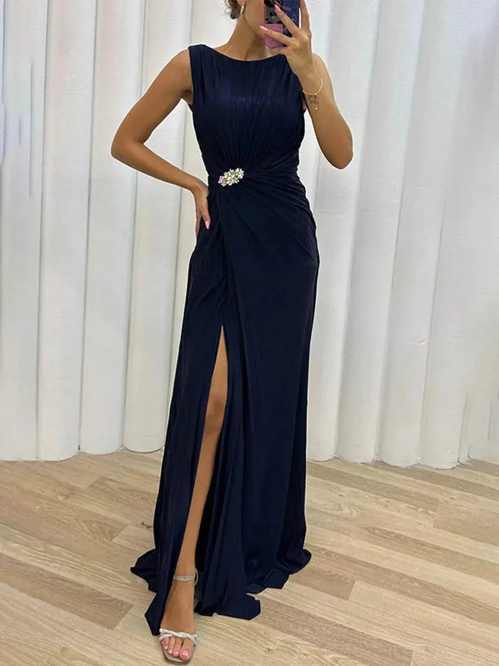 Woman in a three-quarter turn wearing a navy blue pleated slit gown