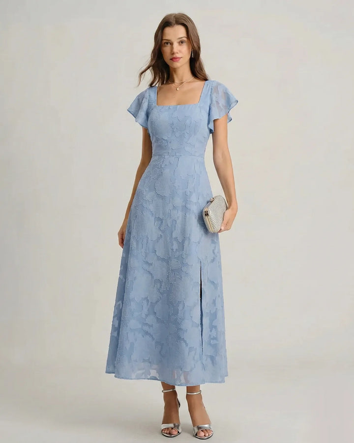 Woman wearing a blue flutter sleeve midi dress, facing forward with arms relaxed at sides