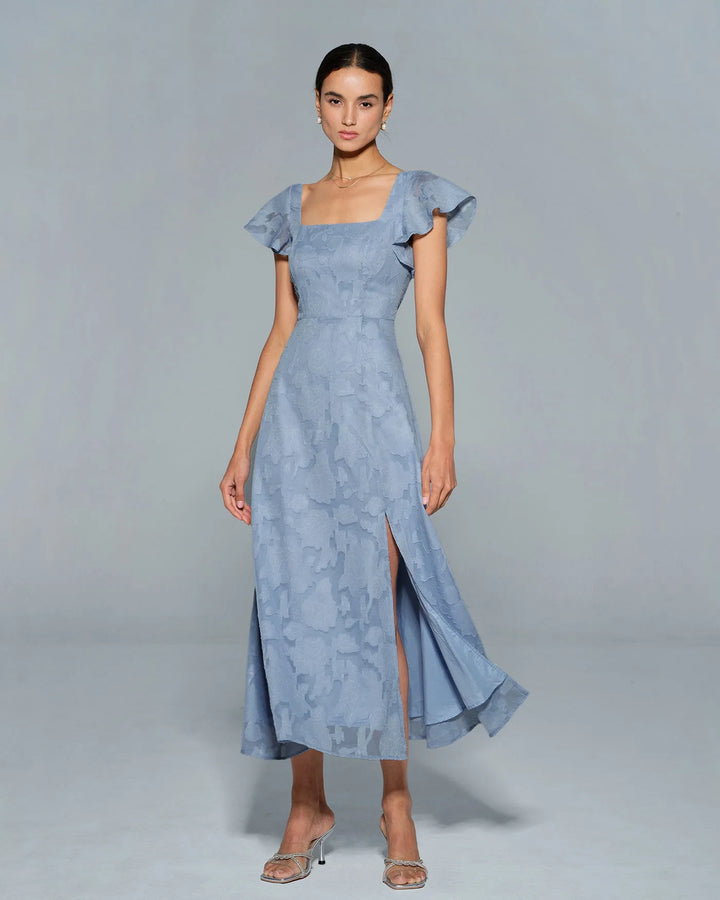 Woman in a blue flutter sleeve midi dress, full-length view from the front