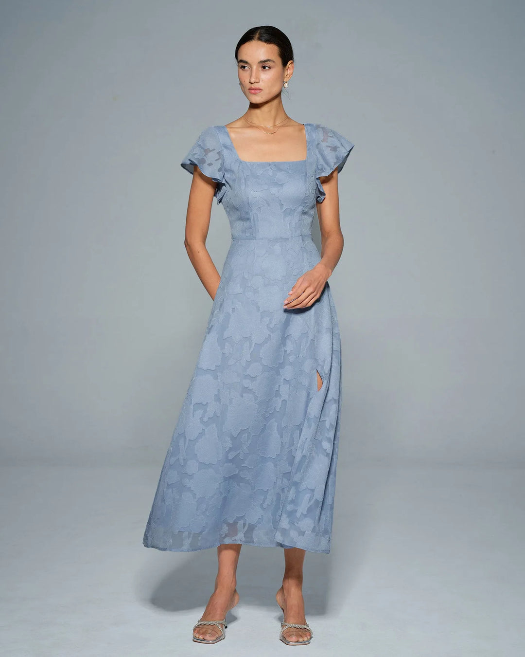 Woman wearing a blue flutter sleeve midi dress, additional styling view