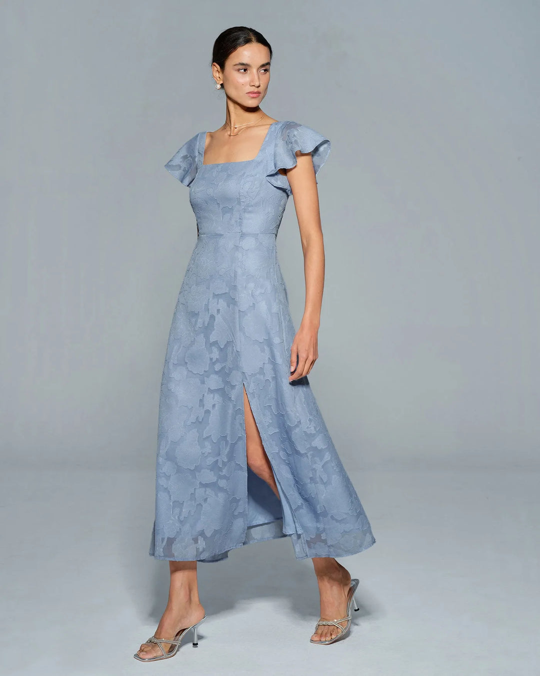 Woman in a blue flutter sleeve midi dress, final alternate angle view