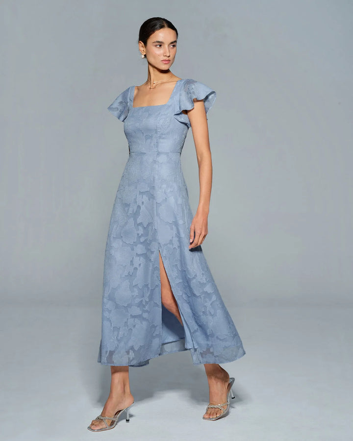Woman in a blue flutter sleeve midi dress, final alternate angle view