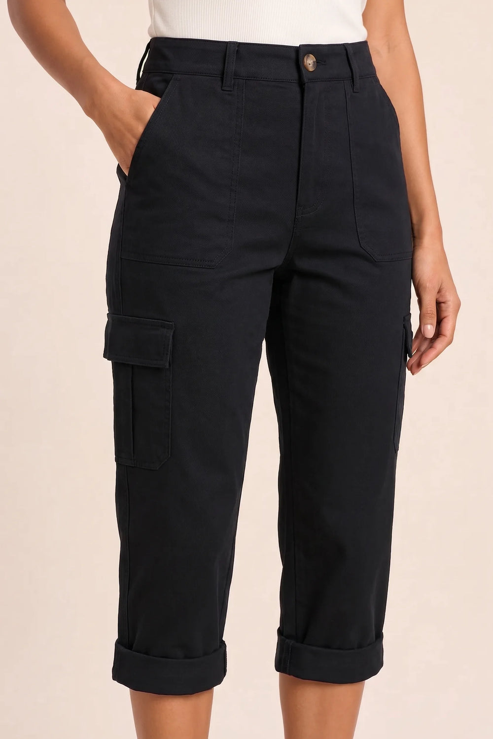 Close-up detail of black cargo capri pants showing roll hem and pocket