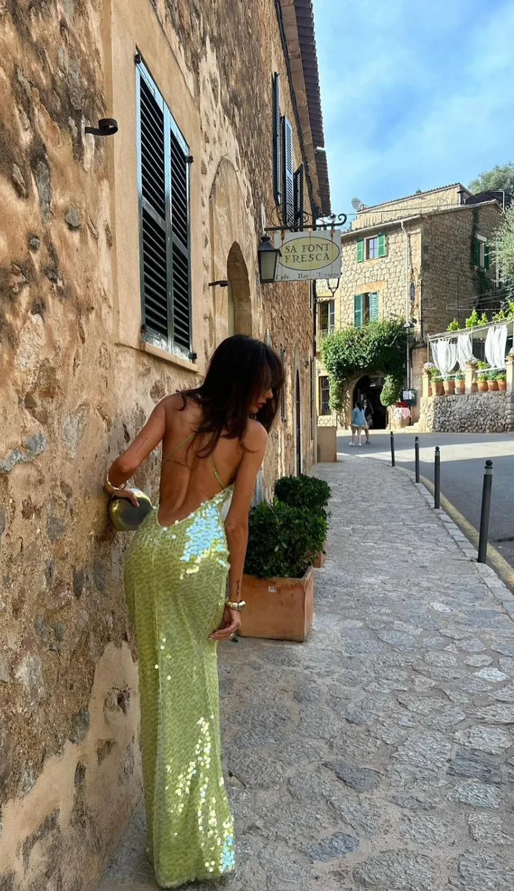 Side view of a woman in a sleek floor-length green sequin backless gown