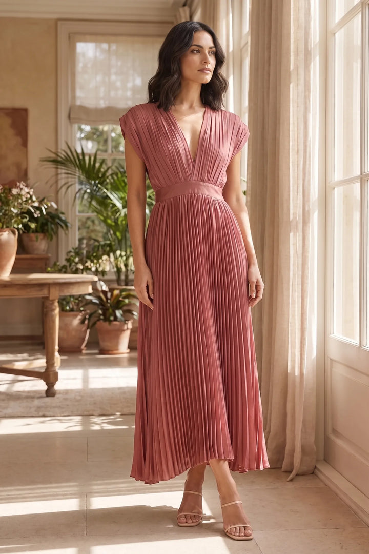 Model wearing an antique pink pleated midi dress in a lifestyle setting