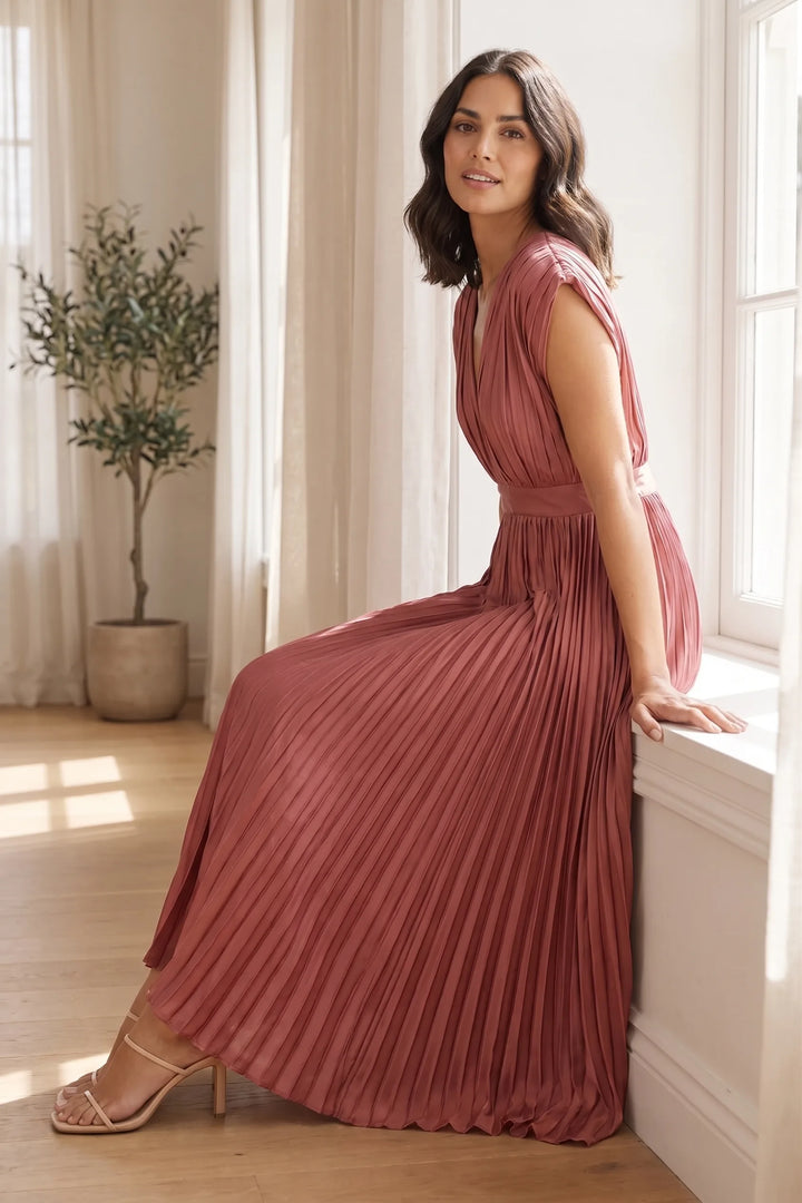 Model wearing an antique pink pleated midi dress in an outdoor lifestyle setting