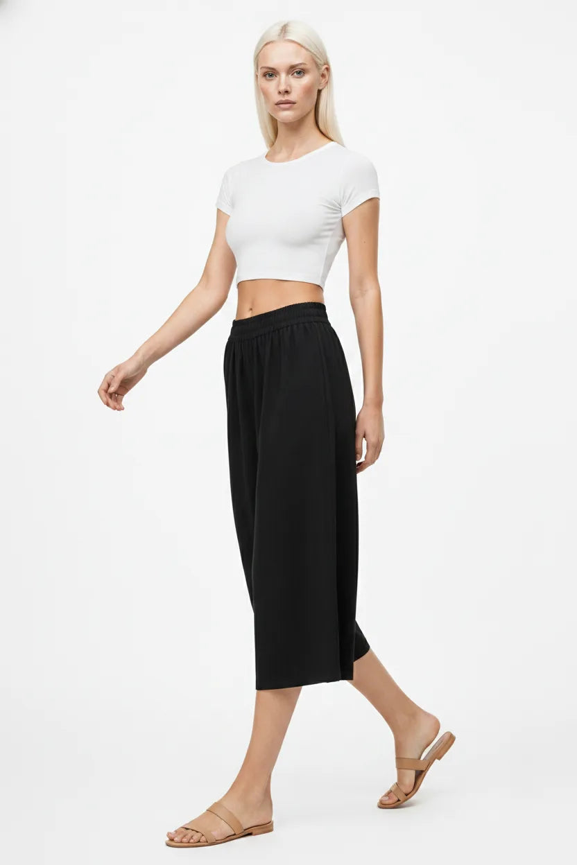Black smocked culotte pants on a model in natural movement