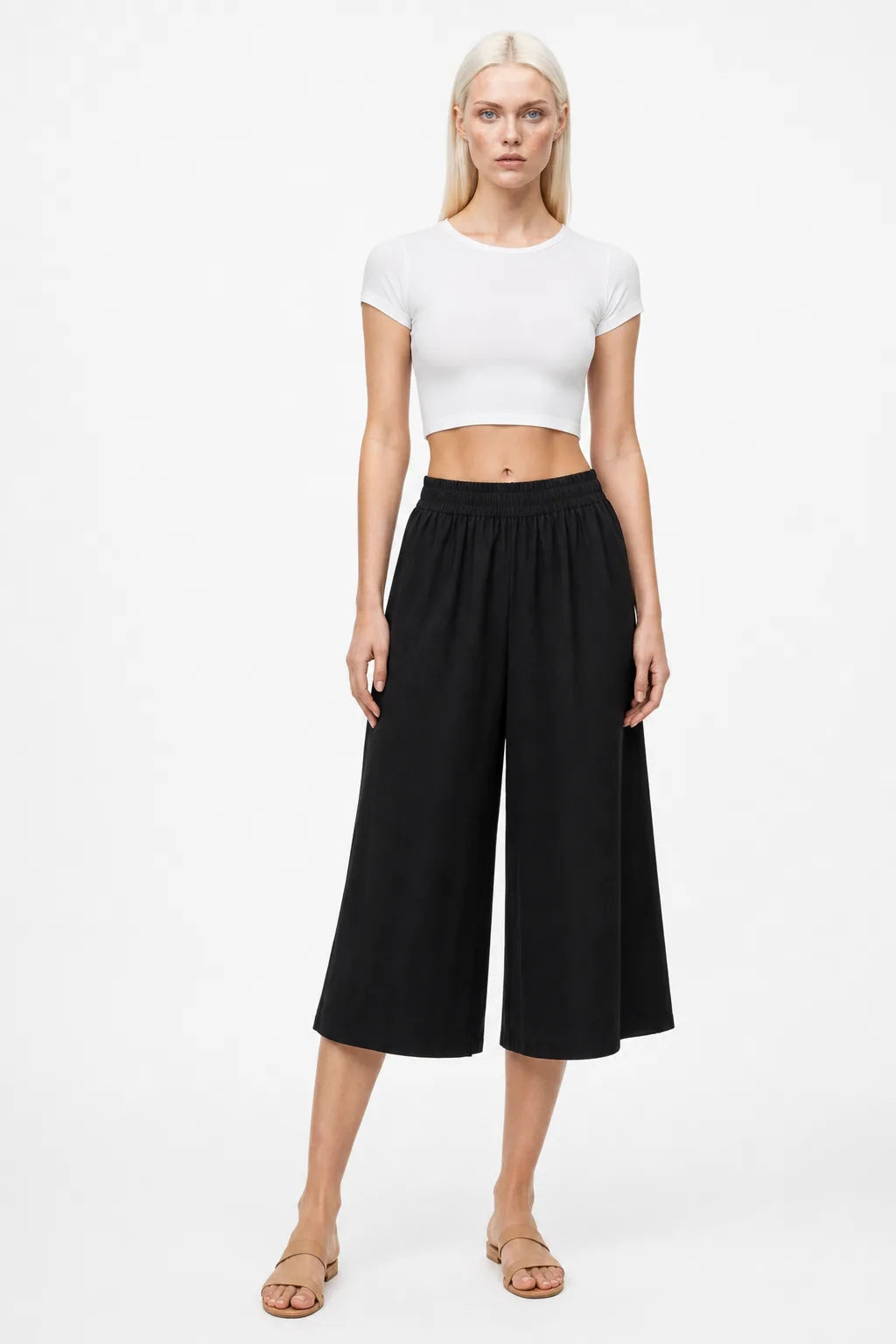 Black smocked culotte pants on a model in a contrapposto stance