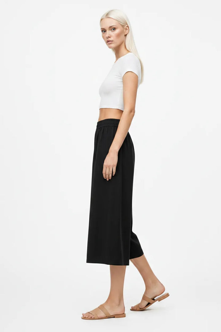 Black smocked culotte pants on a model in a three-quarter turn