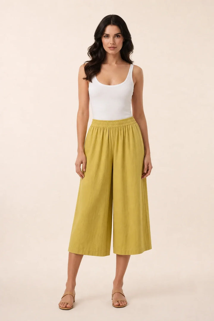 Yellow smocked culotte on model in contrapposto stance, elasticated waistband and wide cropped legs