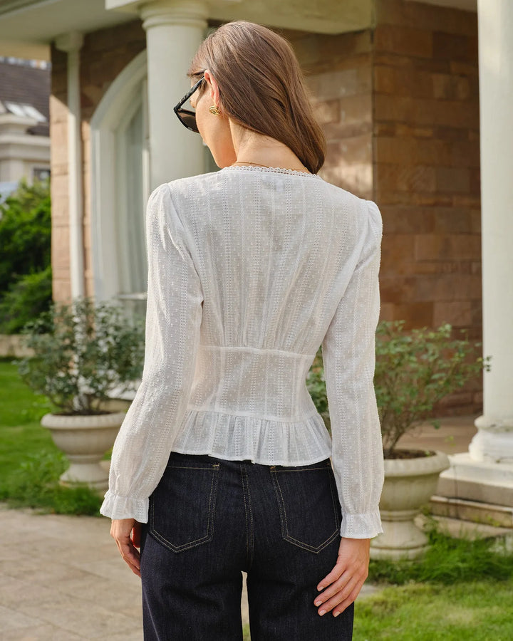 Woman styled in a white broderie corset blouse in a relaxed editorial pose