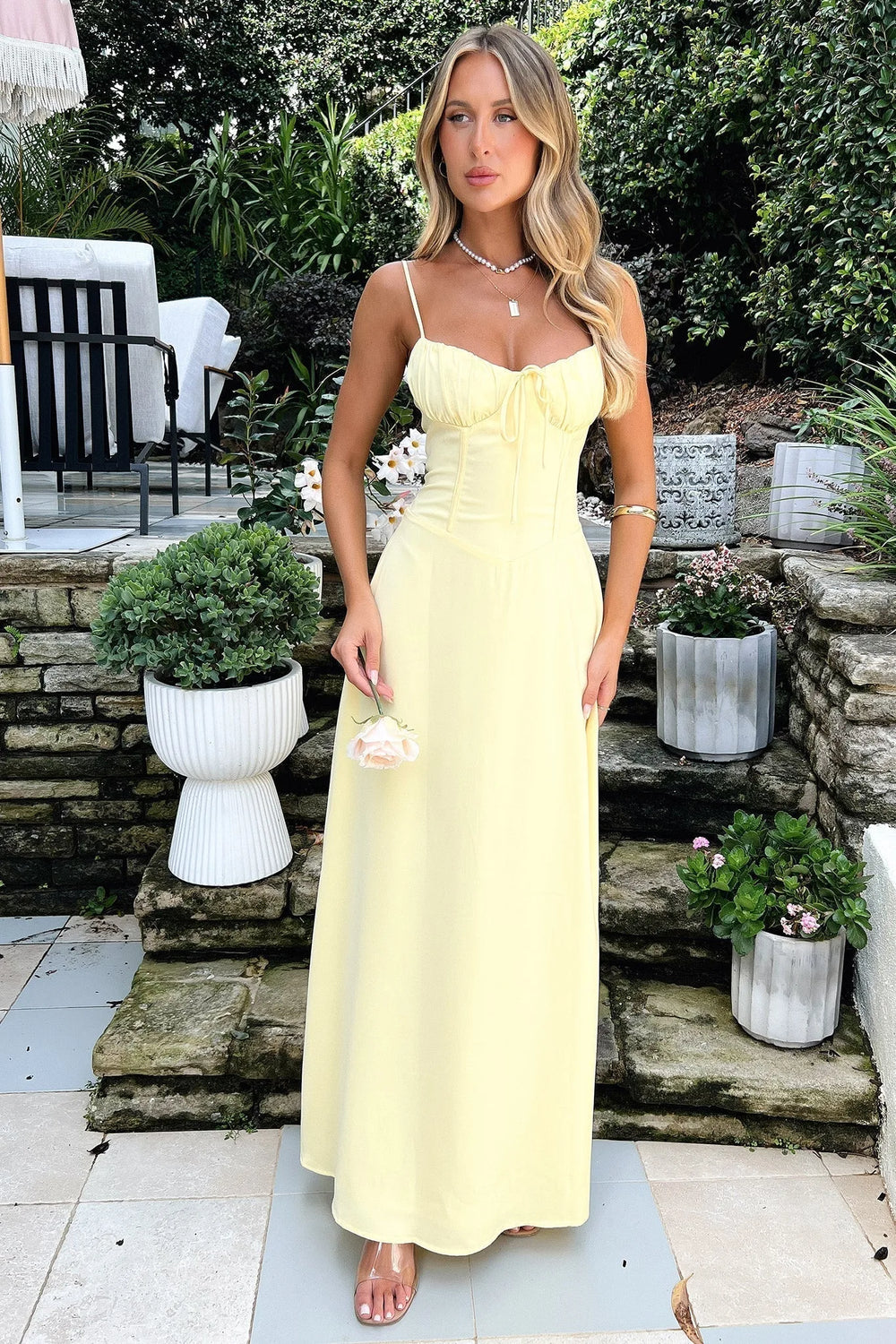 Woman in a yellow corset mermaid maxi dress, posed at a three-quarter turn