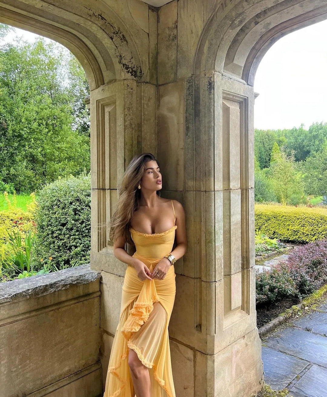 Model wearing a yellow ruffle slit maxi dress, turned away from camera