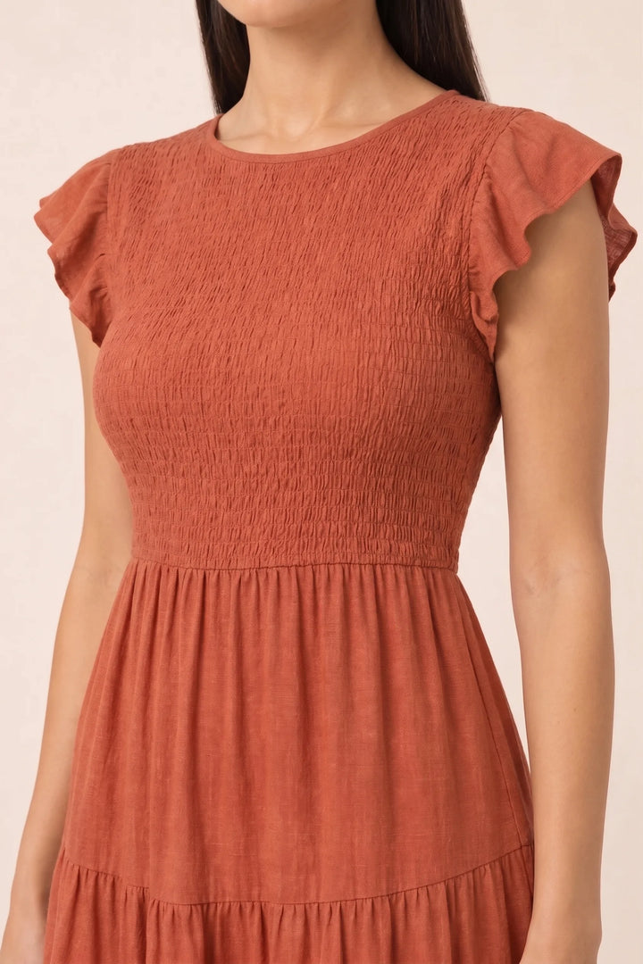 Close-up detail of orange smocked tiered midi dress